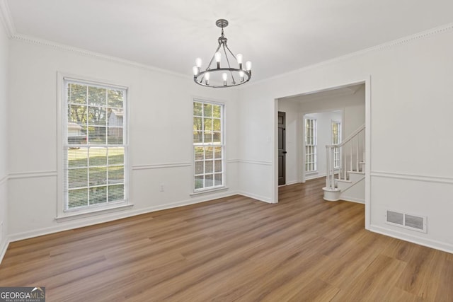 unfurnished dining area with wood-type flooring, a chandelier, and ornamental molding