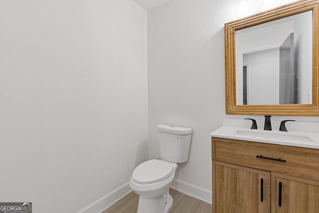 bathroom featuring wood-type flooring, toilet, and vanity