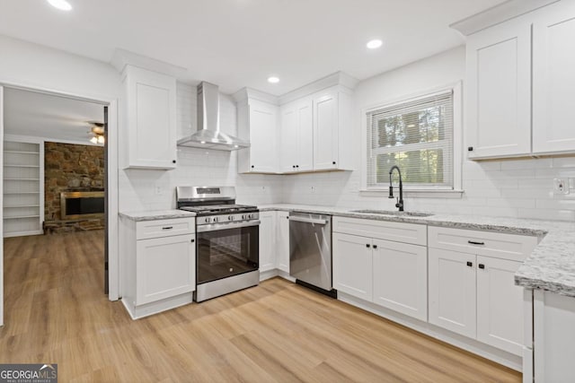 kitchen with sink, white cabinets, stainless steel appliances, and wall chimney exhaust hood