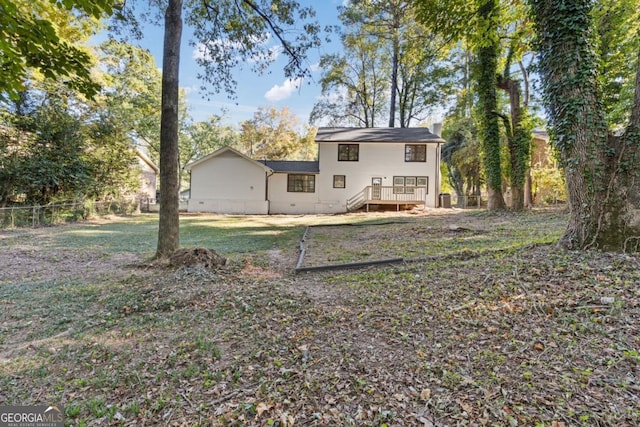 rear view of house featuring a wooden deck and a yard