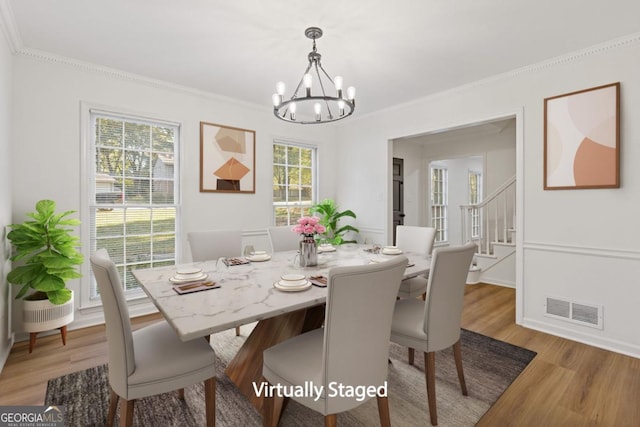 dining area with an inviting chandelier, light hardwood / wood-style flooring, a wealth of natural light, and ornamental molding