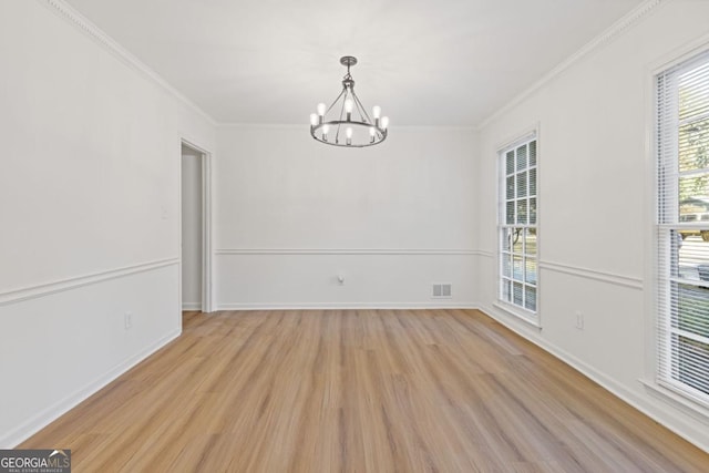 empty room with ornamental molding, light hardwood / wood-style floors, and an inviting chandelier