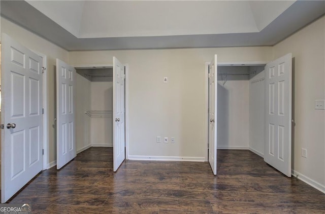 unfurnished bedroom with dark wood-type flooring and two closets