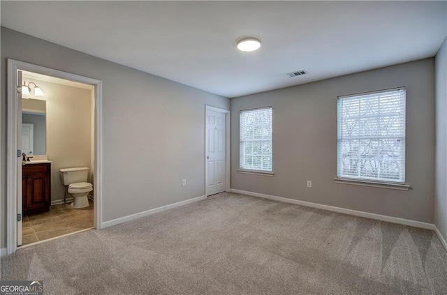 unfurnished bedroom with light carpet, connected bathroom, and a closet