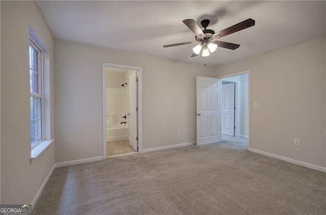 unfurnished bedroom featuring light carpet, connected bathroom, and ceiling fan