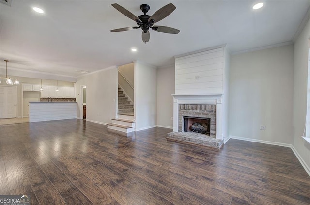 unfurnished living room with a fireplace, ornamental molding, dark hardwood / wood-style floors, and ceiling fan