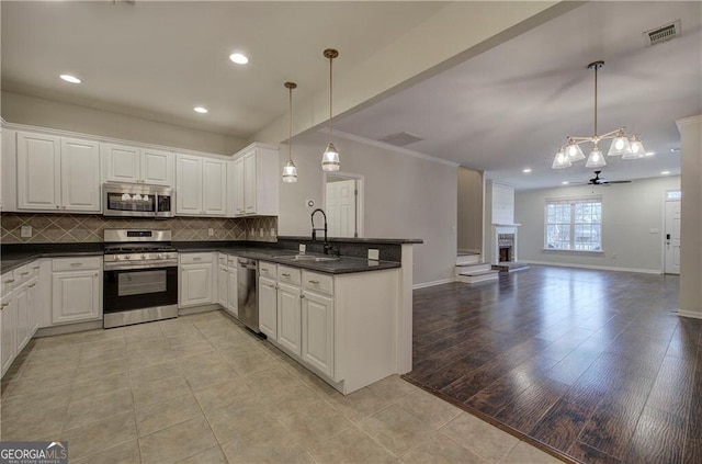 kitchen with pendant lighting, sink, white cabinetry, and appliances with stainless steel finishes