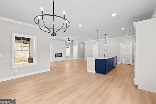 kitchen featuring sink, blue cabinetry, a large fireplace, hanging light fixtures, and a kitchen island with sink