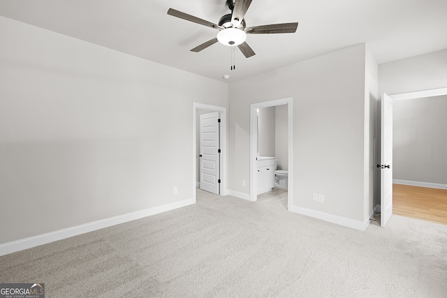 unfurnished bedroom featuring ensuite bathroom, light colored carpet, and ceiling fan