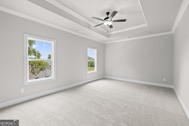 empty room with carpet, a tray ceiling, ornamental molding, and ceiling fan