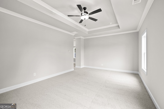 carpeted empty room with a raised ceiling, ceiling fan, and crown molding