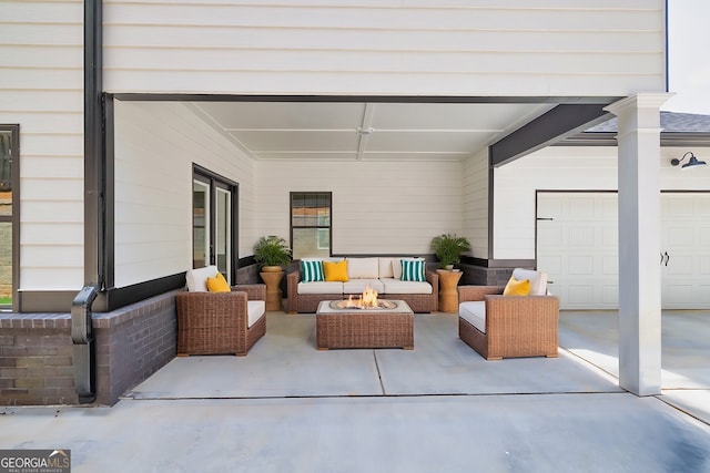 view of patio / terrace featuring a garage and an outdoor living space with a fire pit