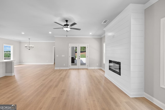 unfurnished living room with a large fireplace, crown molding, light wood-type flooring, and a healthy amount of sunlight