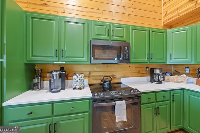 kitchen with stainless steel appliances, wood walls, and green cabinetry