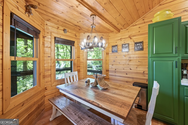 dining space with wooden ceiling, wooden walls, an inviting chandelier, and vaulted ceiling