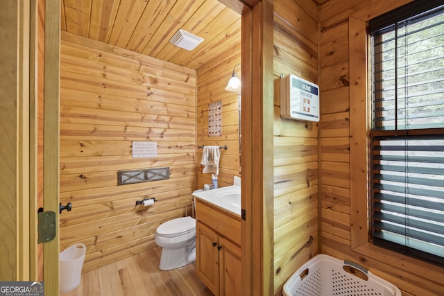 bathroom with toilet, wooden ceiling, hardwood / wood-style flooring, wooden walls, and vanity