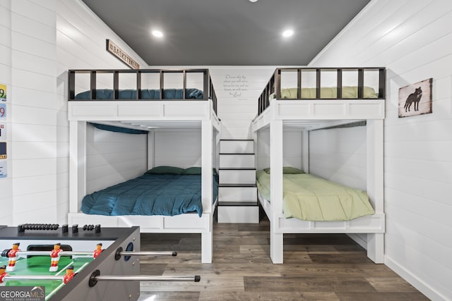 bedroom with hardwood / wood-style floors and wooden walls