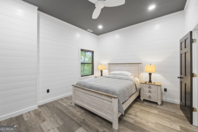 bedroom with ceiling fan, hardwood / wood-style flooring, and wood walls