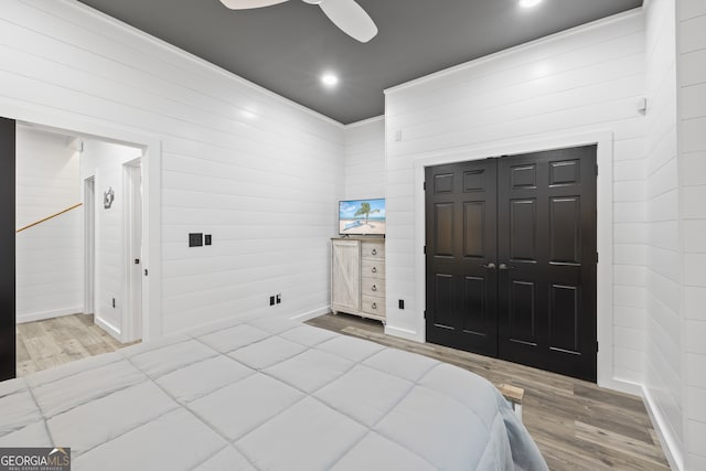 bedroom featuring a closet, ceiling fan, wood walls, and hardwood / wood-style floors