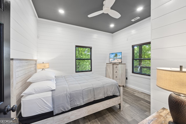 bedroom featuring ceiling fan, wood walls, and hardwood / wood-style flooring