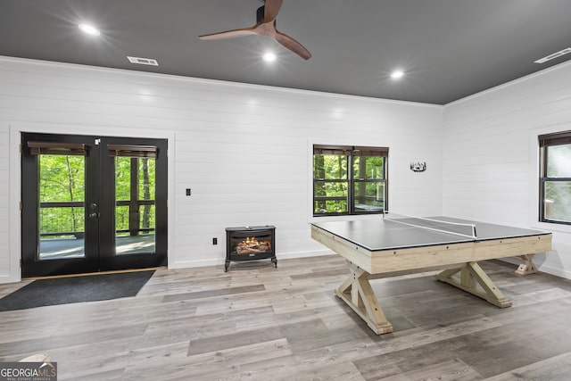 game room featuring a wood stove, french doors, wood walls, and hardwood / wood-style floors