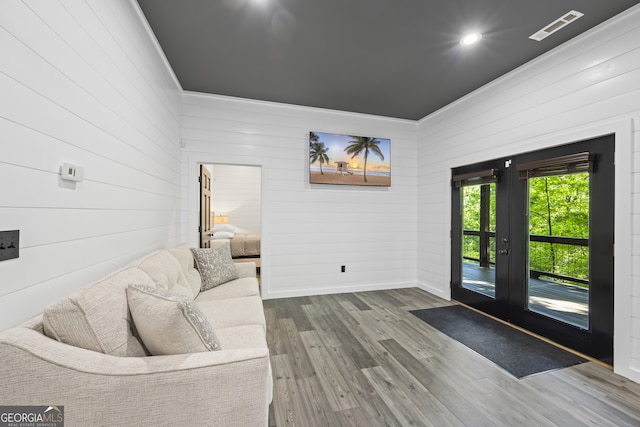 living room featuring hardwood / wood-style floors, wooden walls, and french doors