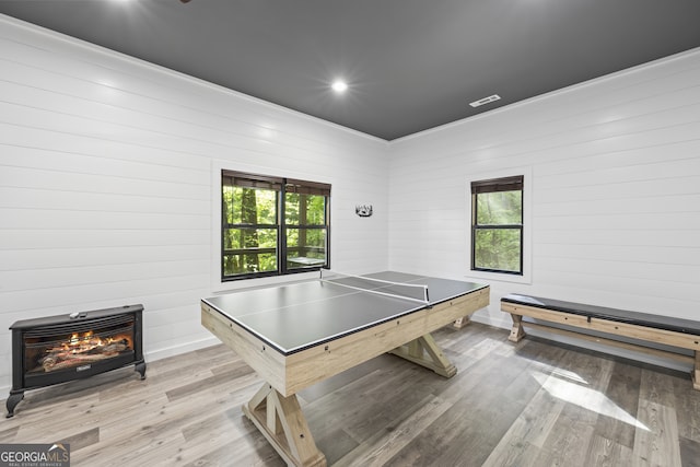 rec room with light hardwood / wood-style flooring and wooden walls