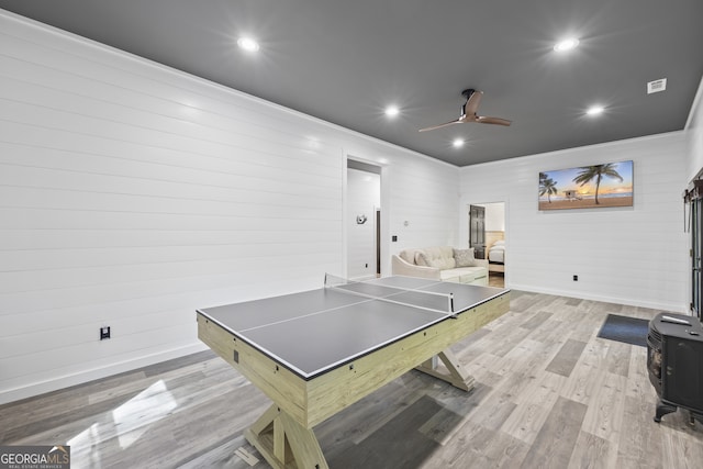 rec room with ceiling fan, light hardwood / wood-style flooring, wooden walls, and crown molding