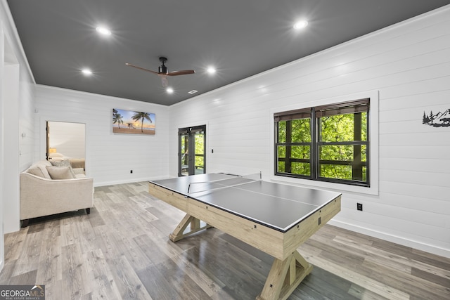 rec room with light hardwood / wood-style floors, a wealth of natural light, and wooden walls