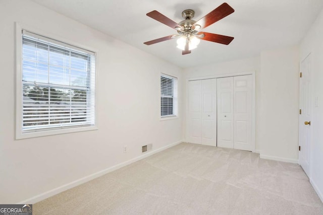 unfurnished bedroom featuring a closet, ceiling fan, and light carpet