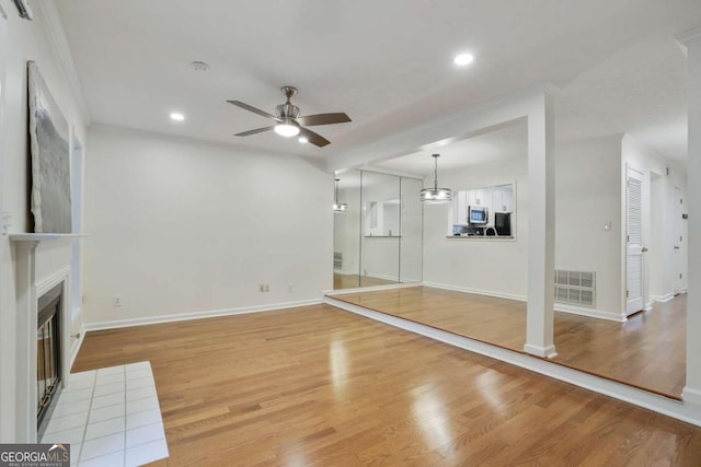 unfurnished living room featuring ceiling fan, crown molding, and light wood-type flooring