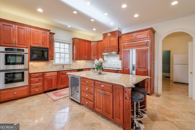 kitchen with a center island, double oven, black microwave, white refrigerator, and sink