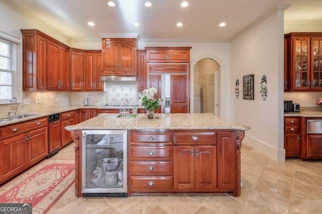 kitchen with ornamental molding, light stone counters, a center island with sink, and beverage cooler