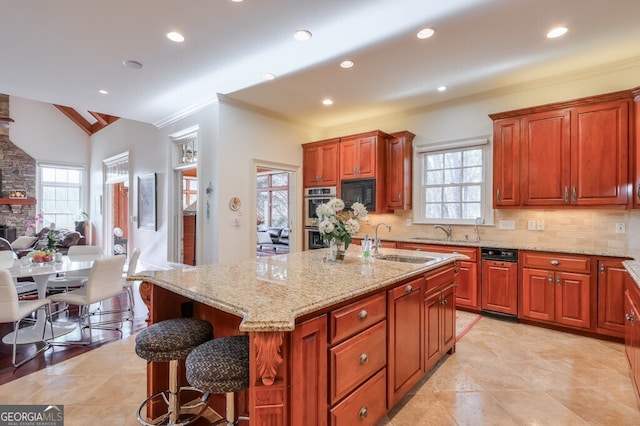 kitchen featuring sink, black microwave, a breakfast bar, an island with sink, and lofted ceiling