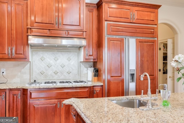 kitchen with white gas cooktop, paneled refrigerator, sink, light stone counters, and decorative backsplash