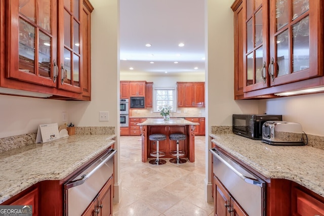 kitchen featuring black microwave, a breakfast bar, stainless steel double oven, and light stone countertops