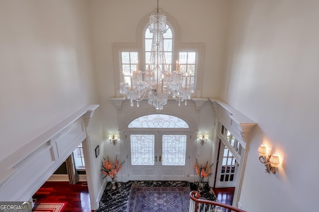 entryway featuring a chandelier, a towering ceiling, and french doors