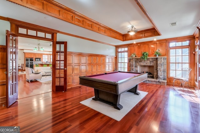 recreation room featuring hardwood / wood-style flooring, a raised ceiling, ornamental molding, and a healthy amount of sunlight