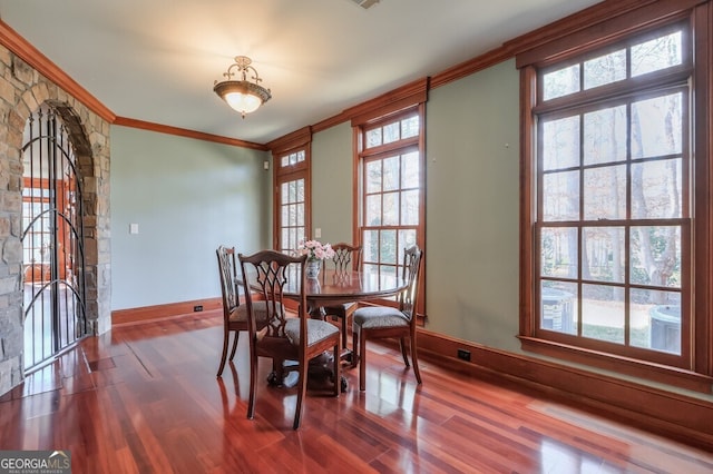 dining space featuring crown molding, hardwood / wood-style flooring, and a healthy amount of sunlight