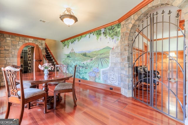 dining area with wood-type flooring and ornamental molding