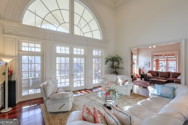 living room featuring a towering ceiling, french doors, and hardwood / wood-style flooring