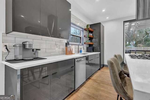 kitchen with dishwasher, sink, gray cabinetry, and light hardwood / wood-style floors