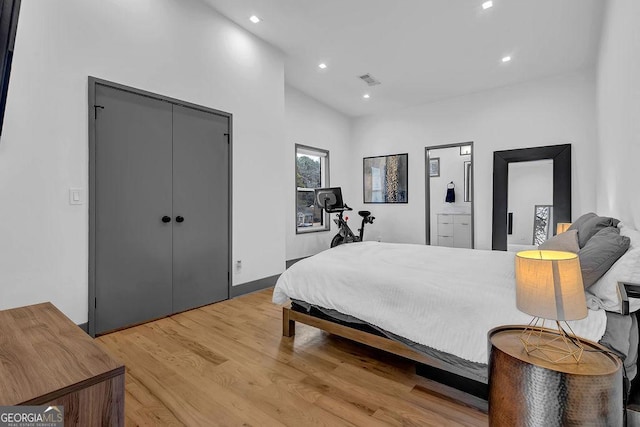 bedroom featuring vaulted ceiling, a closet, and light hardwood / wood-style flooring