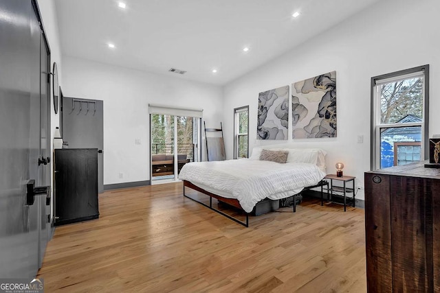 bedroom with access to outside, stainless steel fridge, and light wood-type flooring