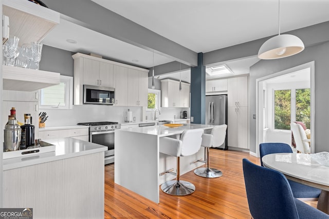 kitchen featuring white cabinetry, hanging light fixtures, and stainless steel appliances