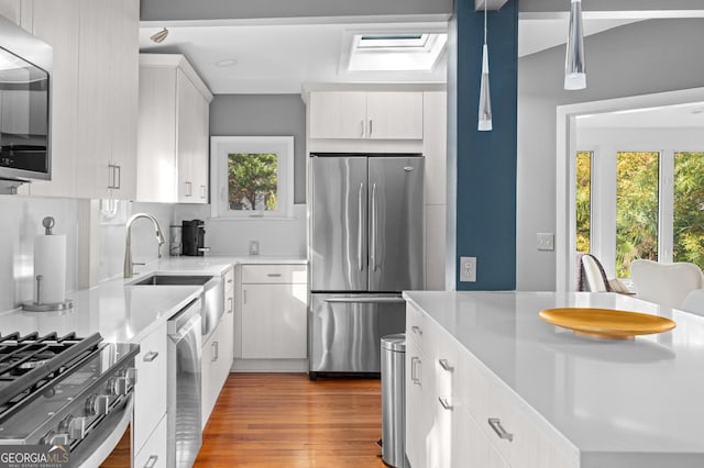 kitchen featuring white cabinetry, a wealth of natural light, pendant lighting, and stainless steel appliances