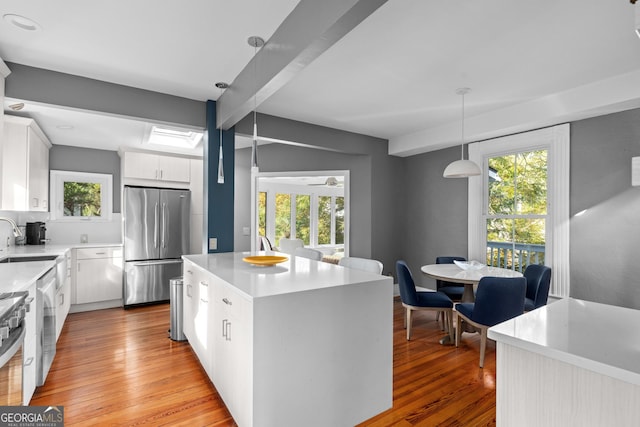 kitchen featuring a center island, light hardwood / wood-style floors, white cabinets, pendant lighting, and stainless steel fridge