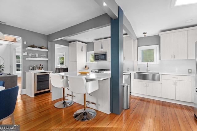 kitchen featuring sink, decorative light fixtures, white cabinets, light hardwood / wood-style flooring, and wine cooler