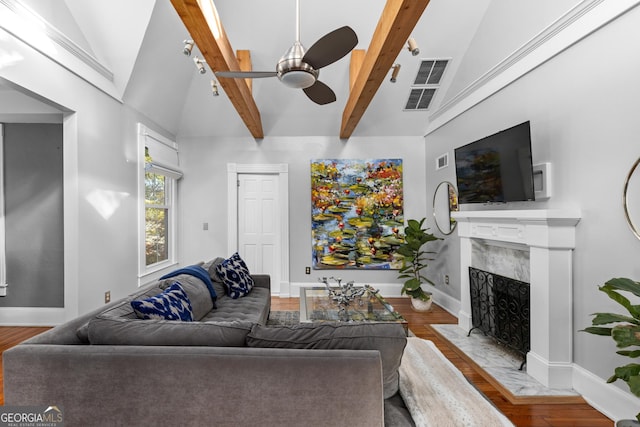 living room featuring hardwood / wood-style flooring, ceiling fan, a fireplace, and lofted ceiling with beams