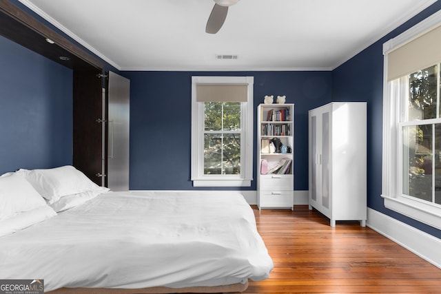 bedroom with ceiling fan, ornamental molding, and dark hardwood / wood-style flooring